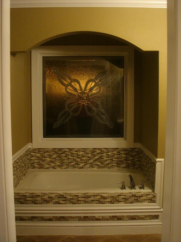 Custom tile work, an arched surround, and a great picture window make this bathroom inviting.