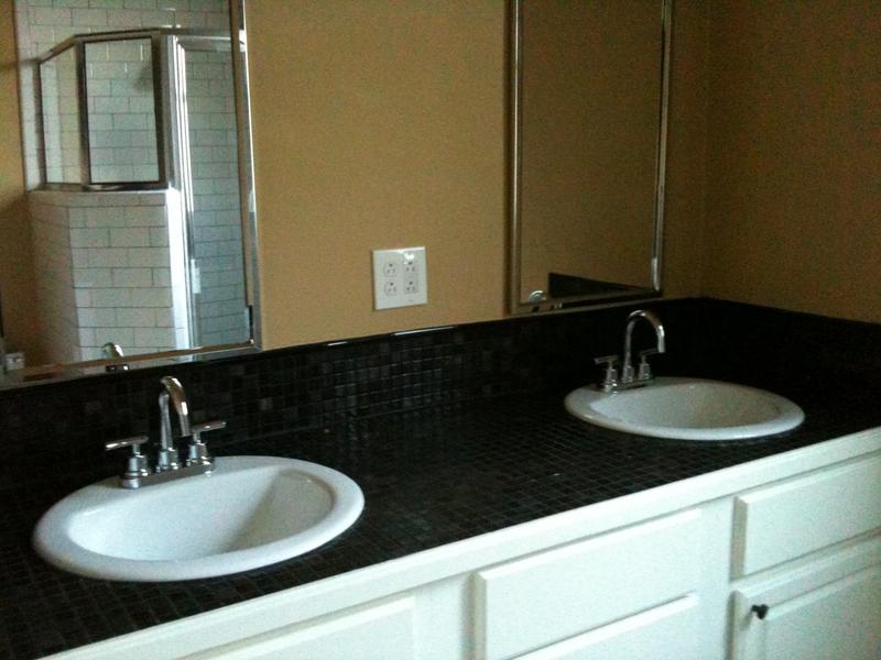 Dual sink, tiled vanity with subway tiled shower in background