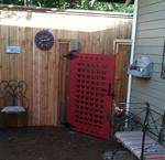 A bold, red gate disguises a storage shed at the side of the house.